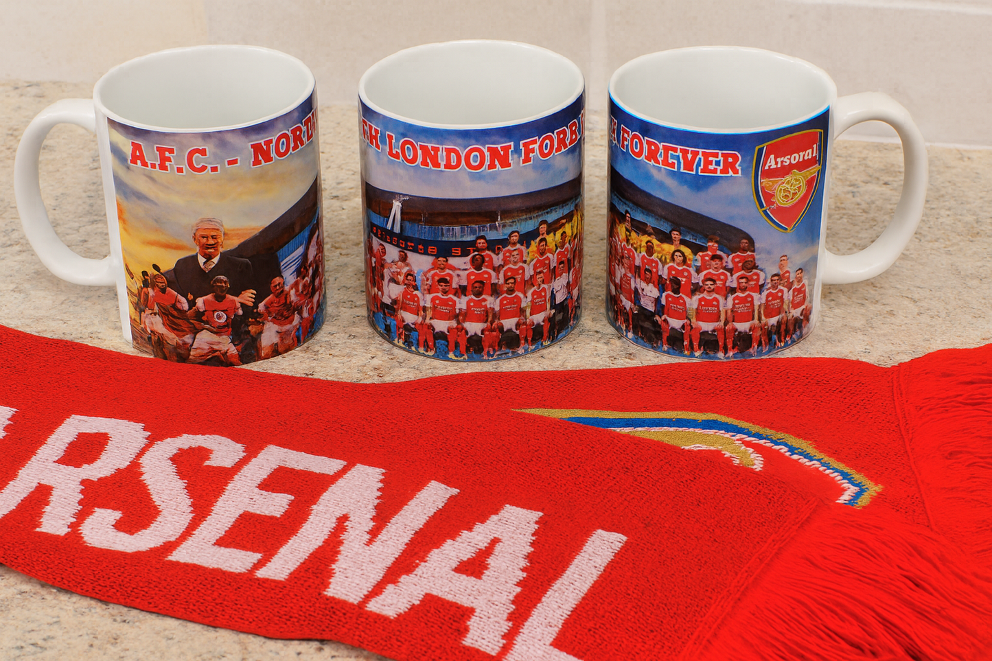 Three Arsenal-themed mugs and a red scarf with 'Arsenal' branding on a light background.