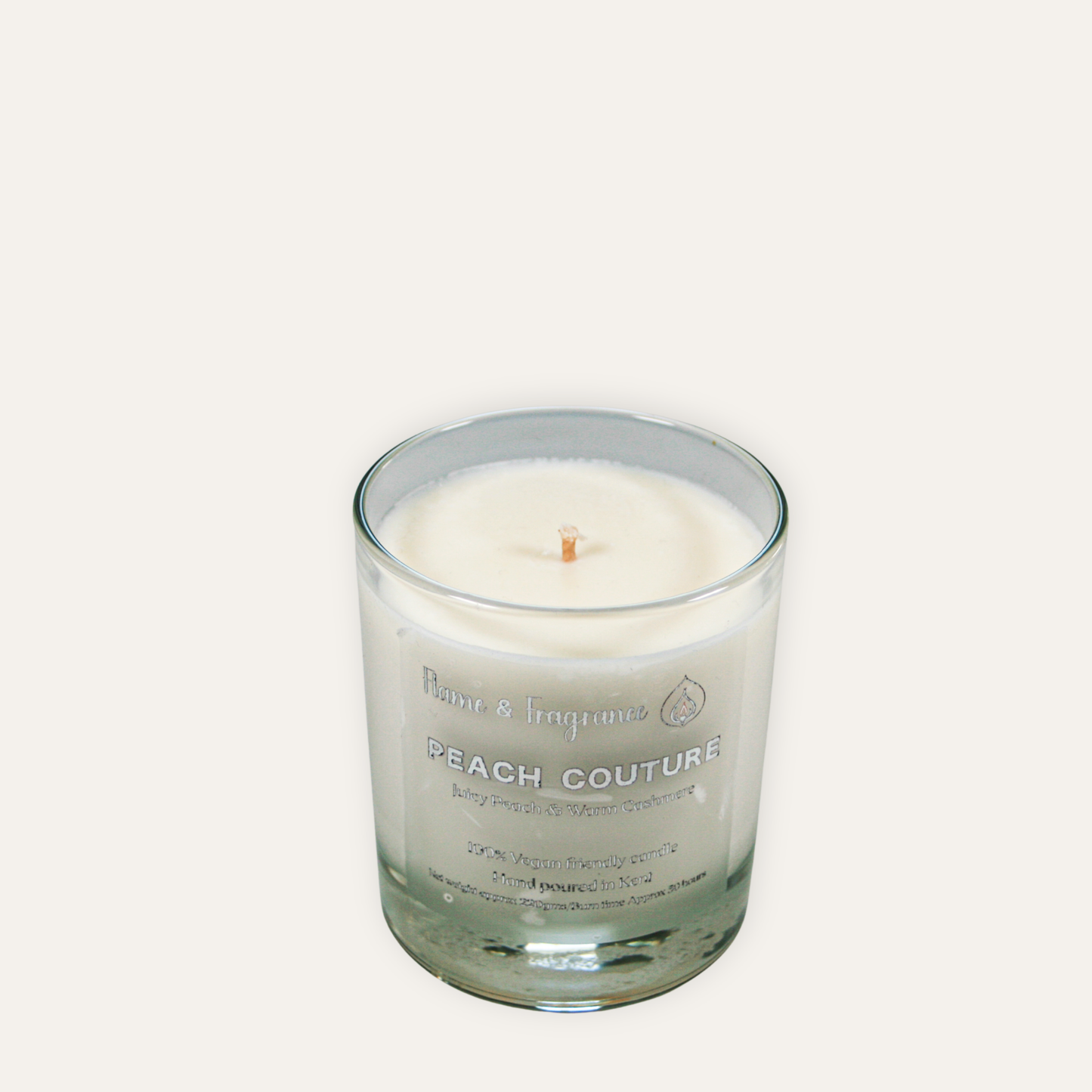 Candle in a glass jar labeled 'Peach Couture' on a white background