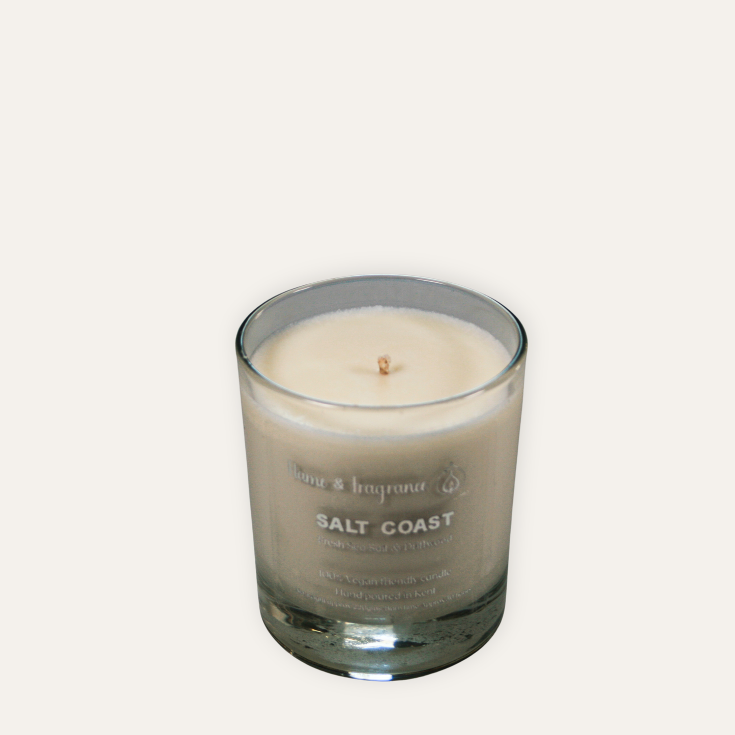 Candle in a glass jar labeled 'Salt Coast' on a light gray background