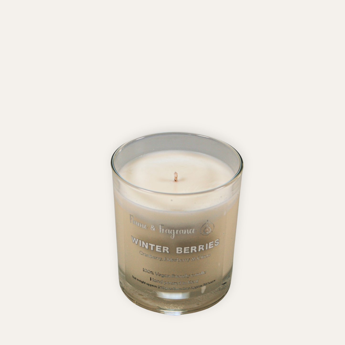 Candle in a glass jar labeled 'Winter Berries' on a white background