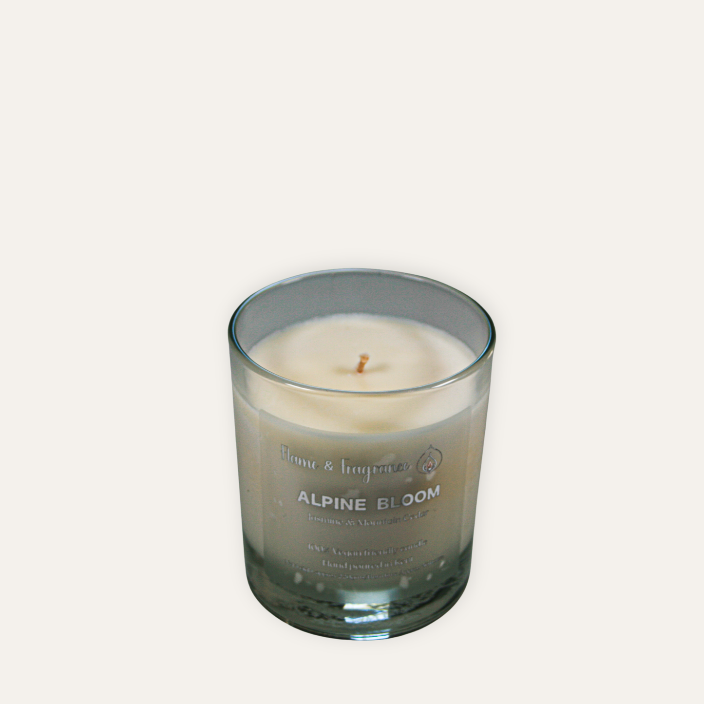 Candle in a glass jar labeled 'Alpine Bloom' on a light gray background