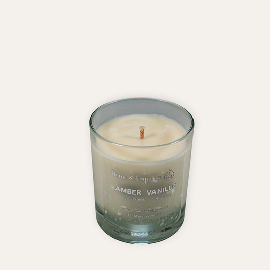 Candle in a glass jar labeled 'Amber Vanille' on a light gray background