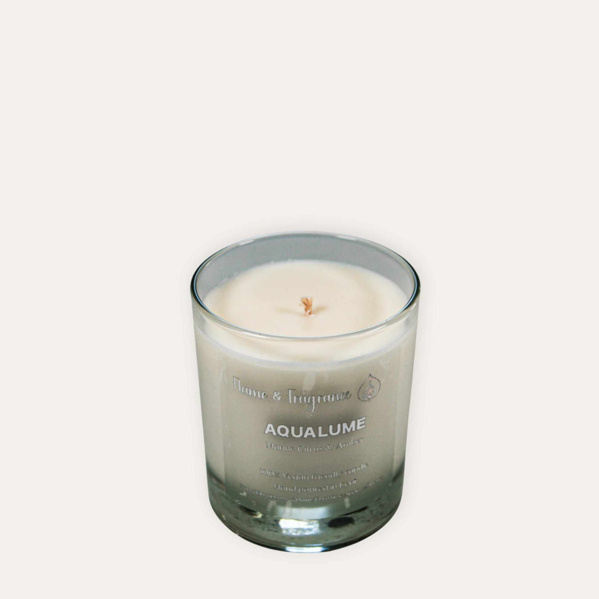 Candle in a glass jar labeled 'Aqualume' on a light gray background