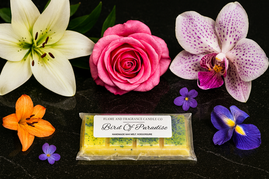 Fragrance wax melt bar labelled 'Bird Of Paradise' surrounded by colorful flowers on a dark surface