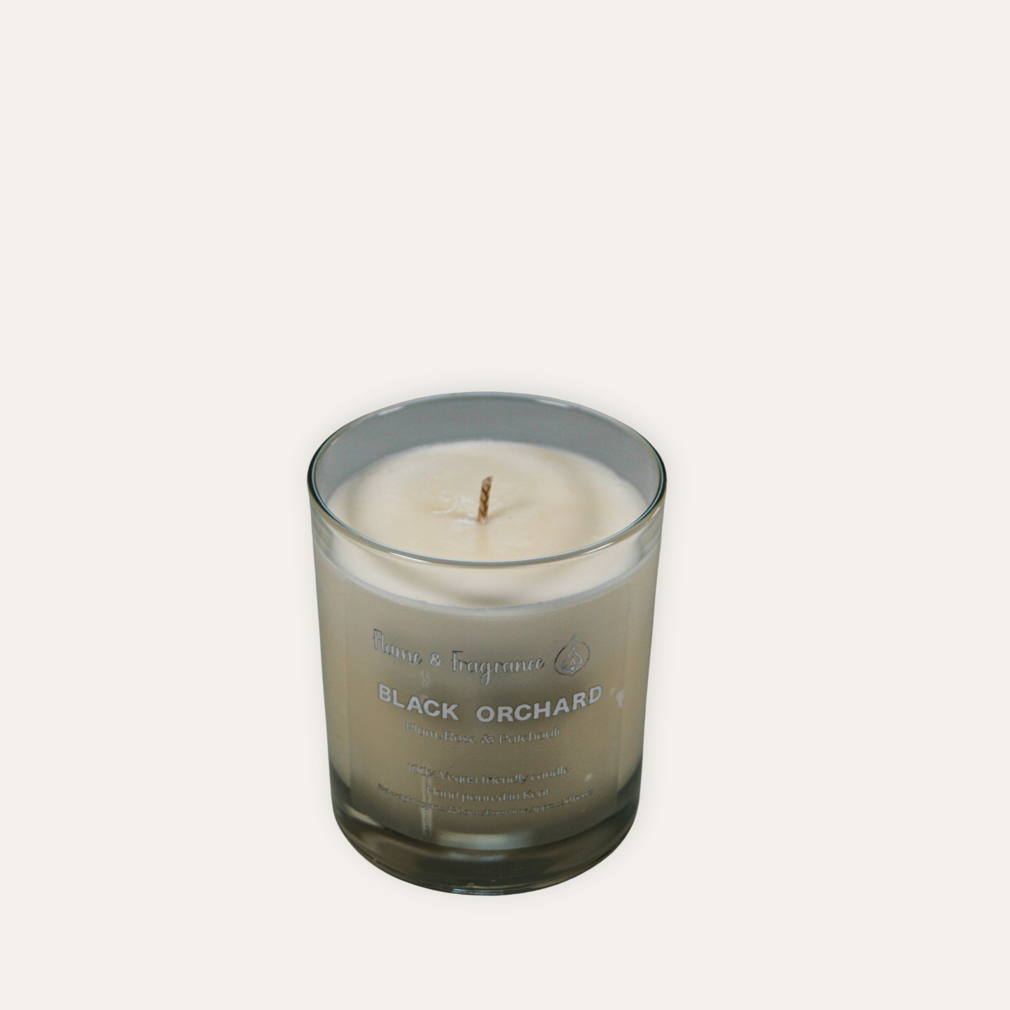 Candle in a glass jar labeled 'Black Orchard' on a white background