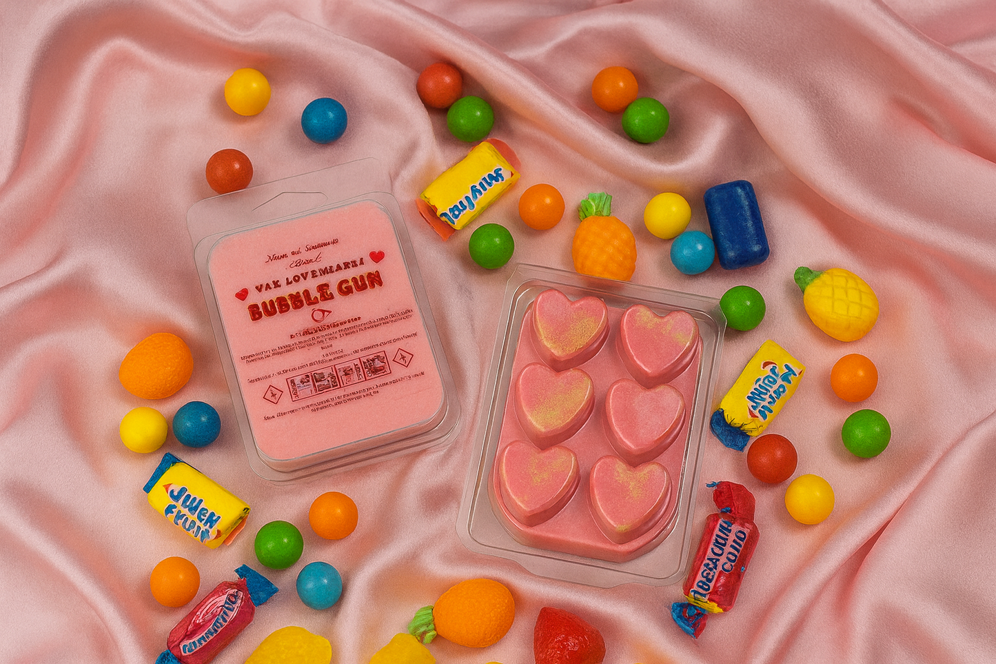 Assorted colorful bubble gum and candy on a pink fabric background surrounding heart-shaped wax melts.