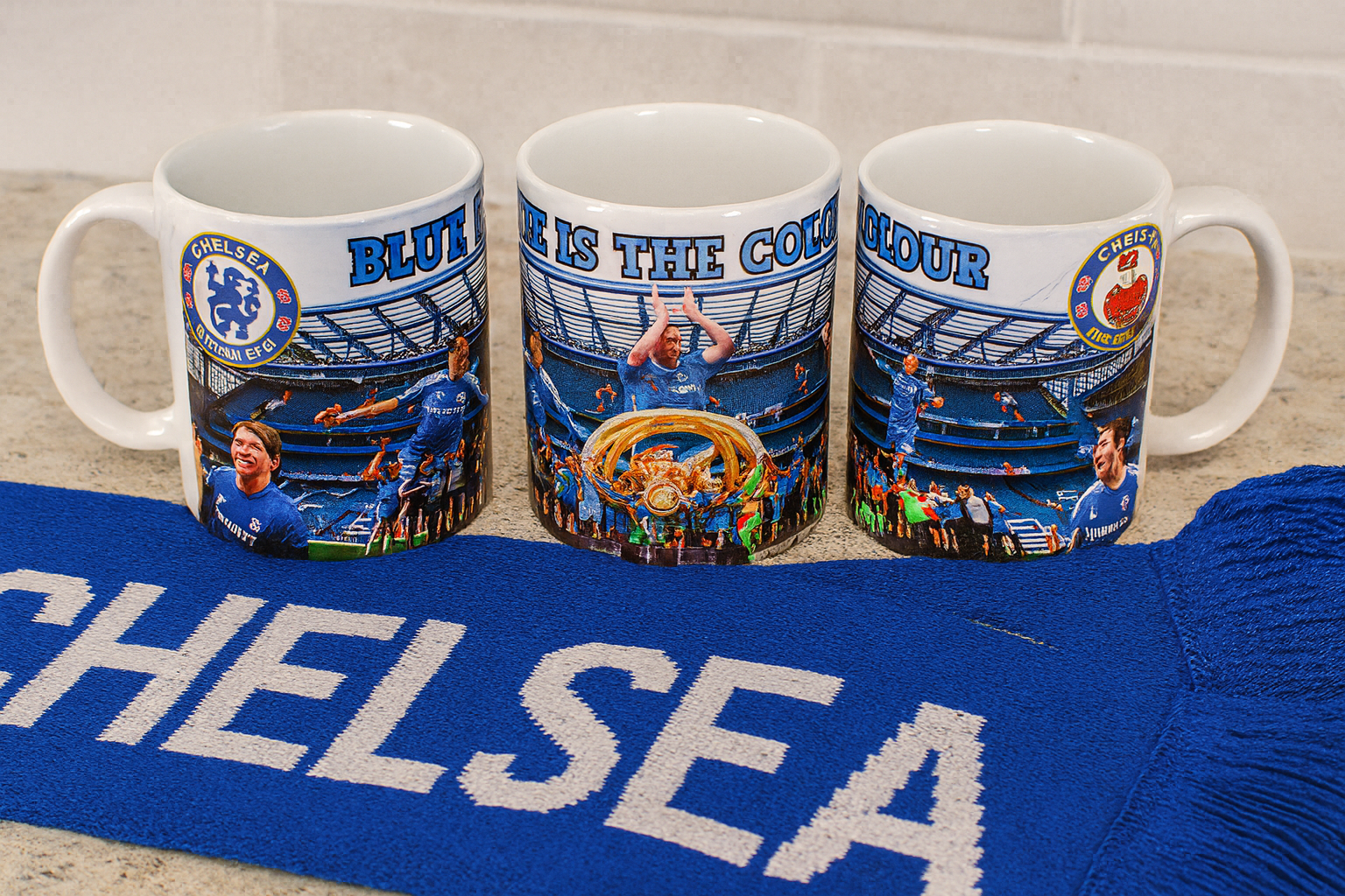 Three mugs with Chelsea FC graphics on a blue blanket with 'Chelsea' branding.