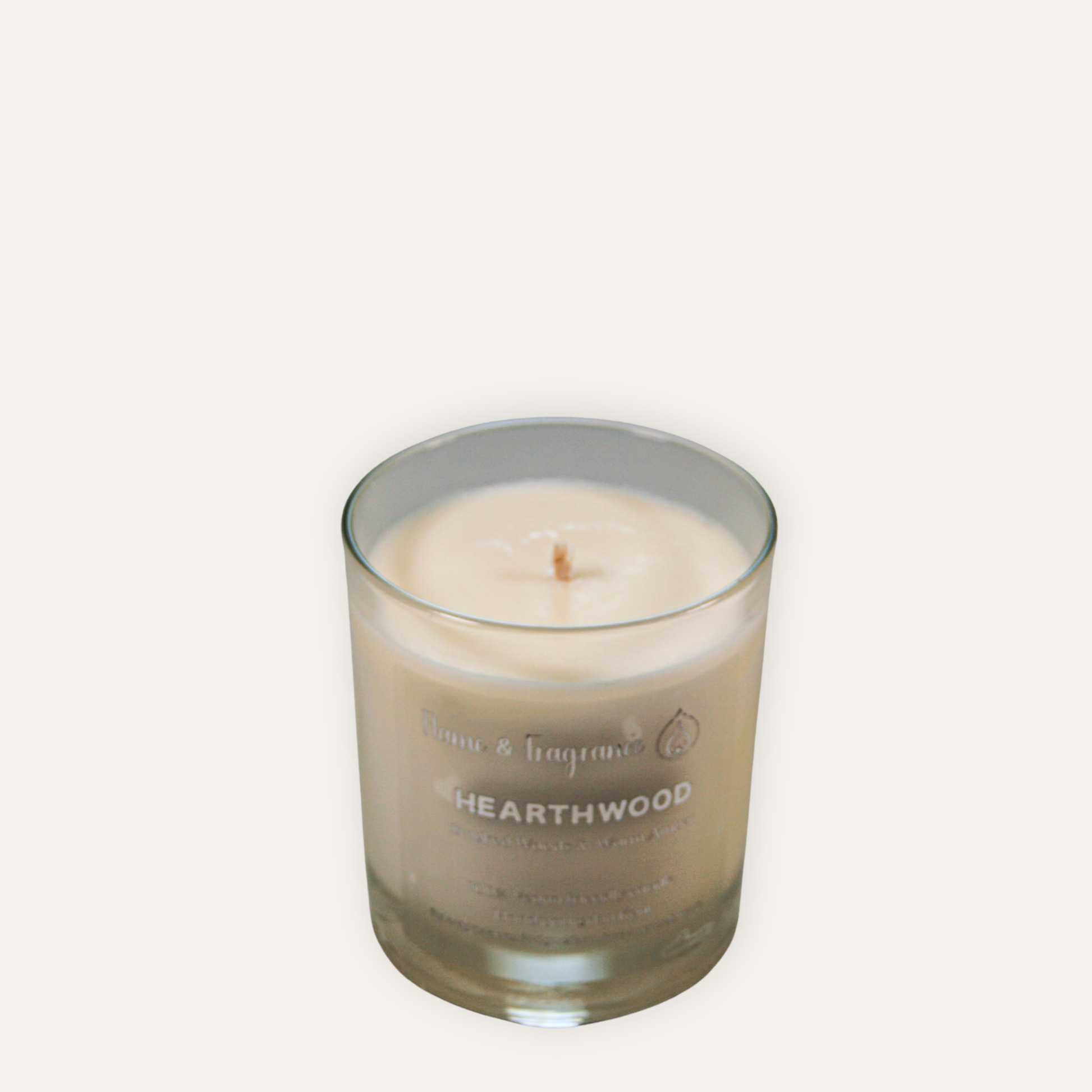 Candle in a glass jar labeled 'Hearthwood' on a white background