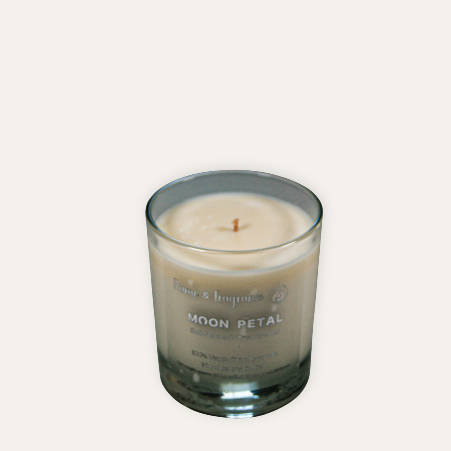 Candle in a glass jar labeled 'Moon Petal' on a light gray background