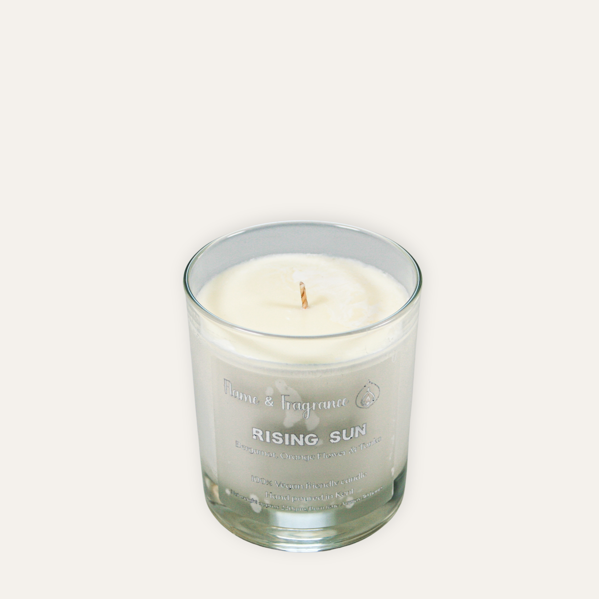 Glass candle labeled 'Rising Sun' on a white background