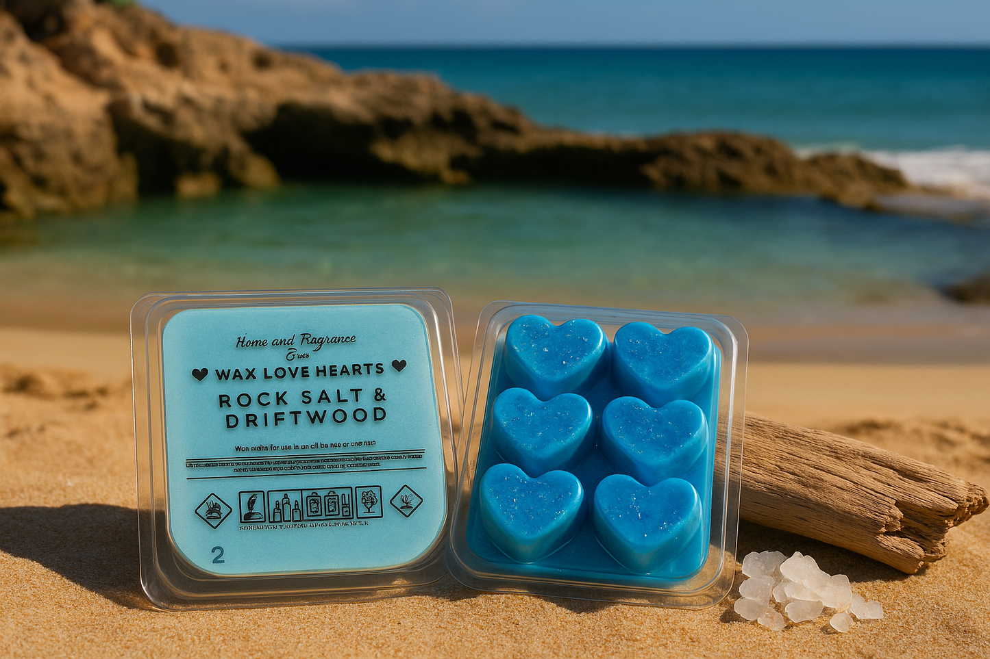 Packaged heart-shaped wax melts on a beach with a pile of Rock Salt and a piece of driftwood.