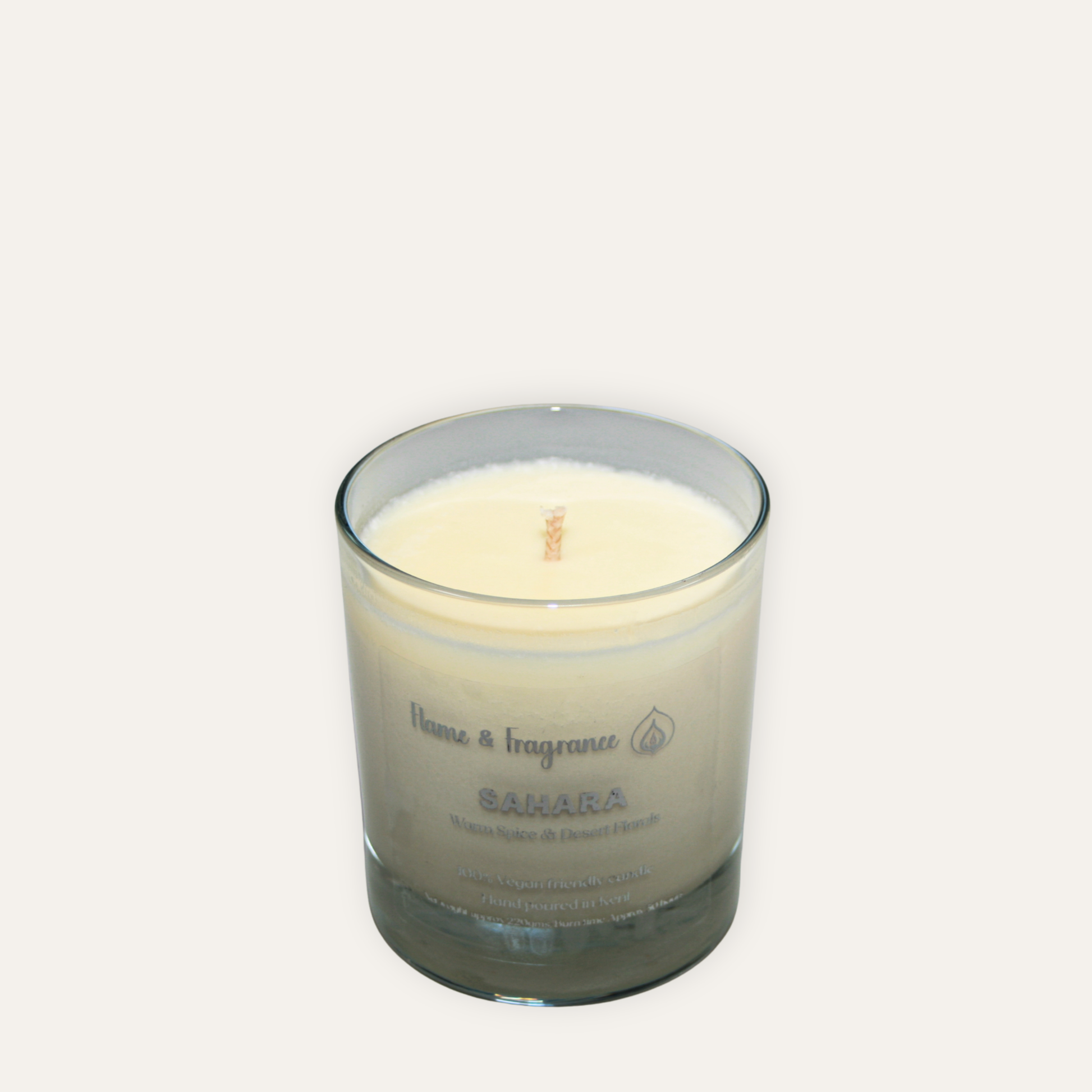 Candle in a glass jar labeled  'Sahara' on a white background