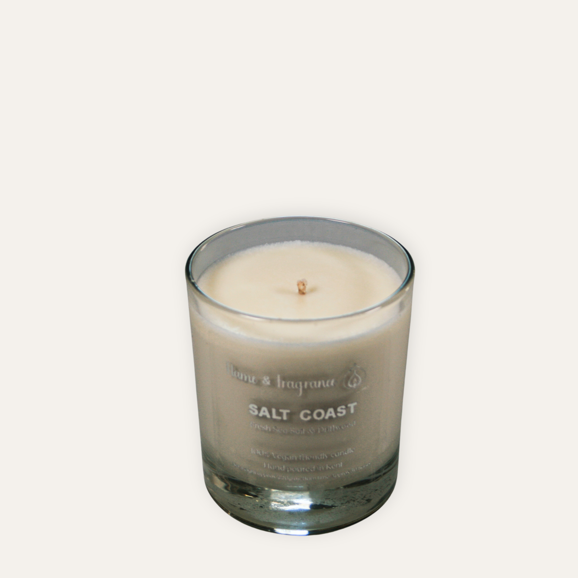 Candle in a glass jar labeled 'Salt Coast' on a light gray background