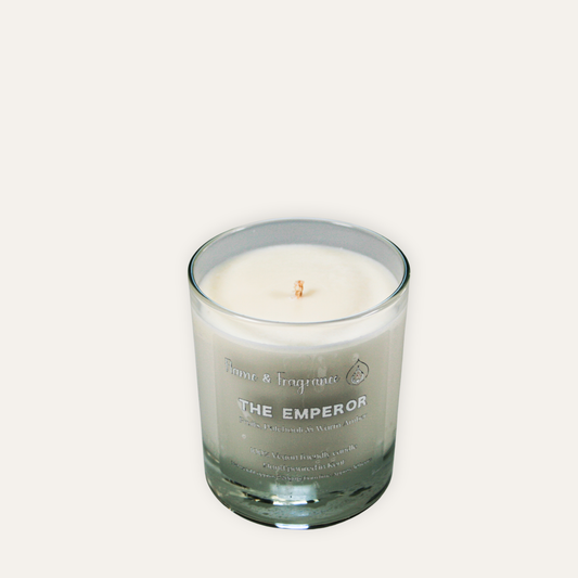 Candle in a glass jar labeled 'The Emperor' on a light gray background