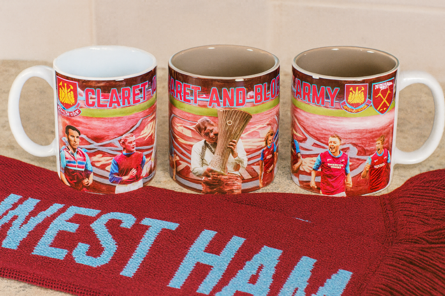 Three mugs with sports team graphics on a West Ham scarf.