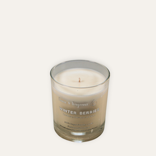 Candle in a glass jar labeled 'Winter Berries' on a white background